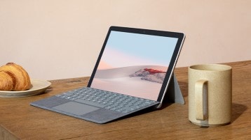 Surface Go 2 on a tabletop with mug and croissant