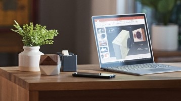 A laptop displaying PowerPoint sits on a table